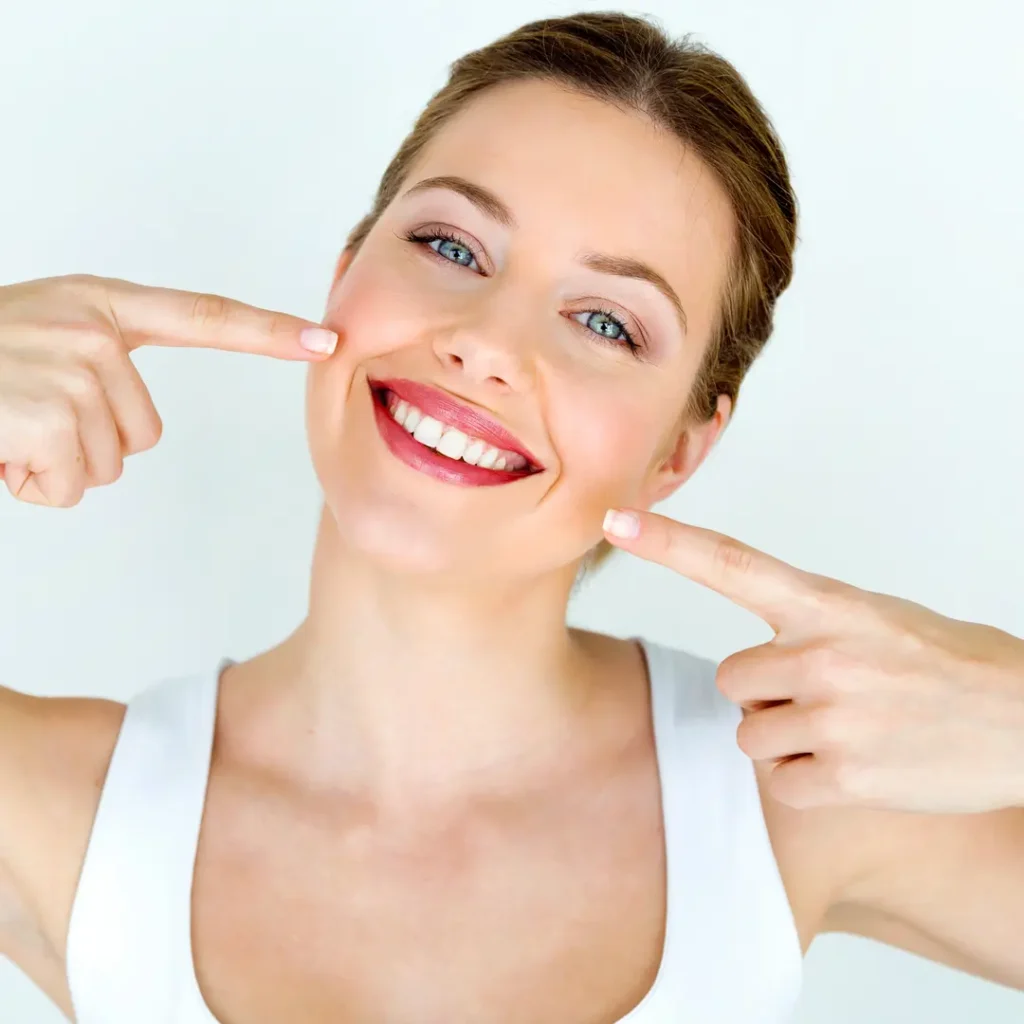 Donna sorridente indica i denti perfetti, risultato di trattamenti di estetica dentale a Torino