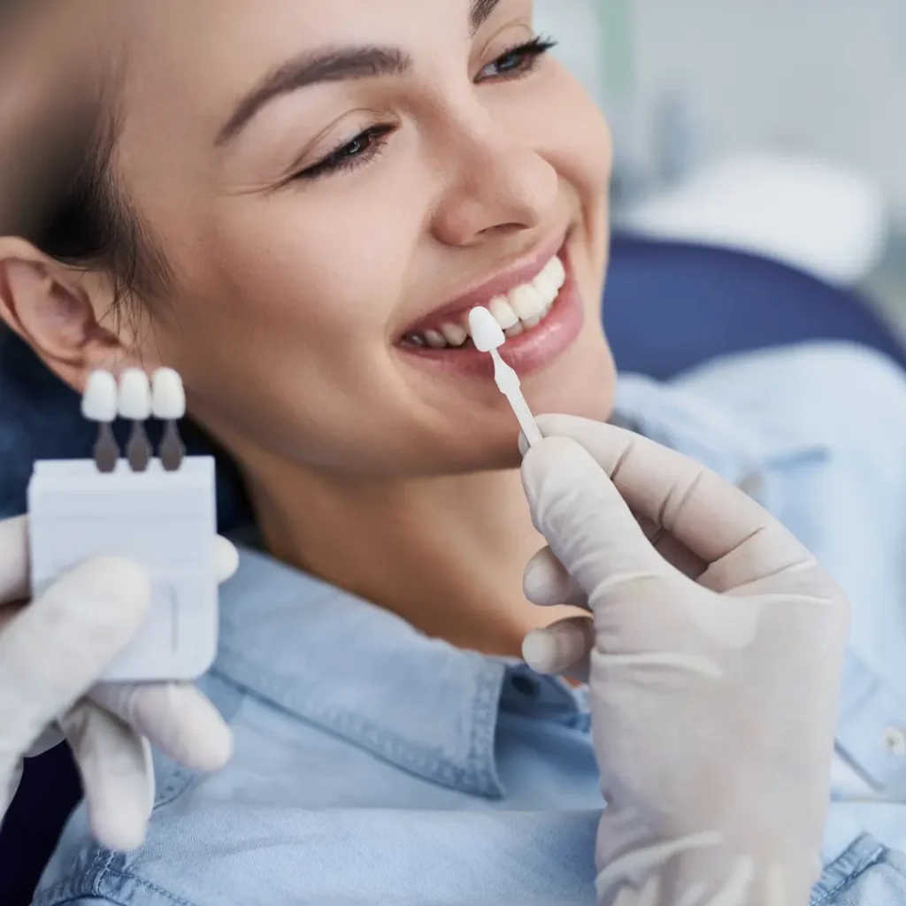 Dentista seleziona la tonalità di faccette dentali per migliorare il sorriso della paziente