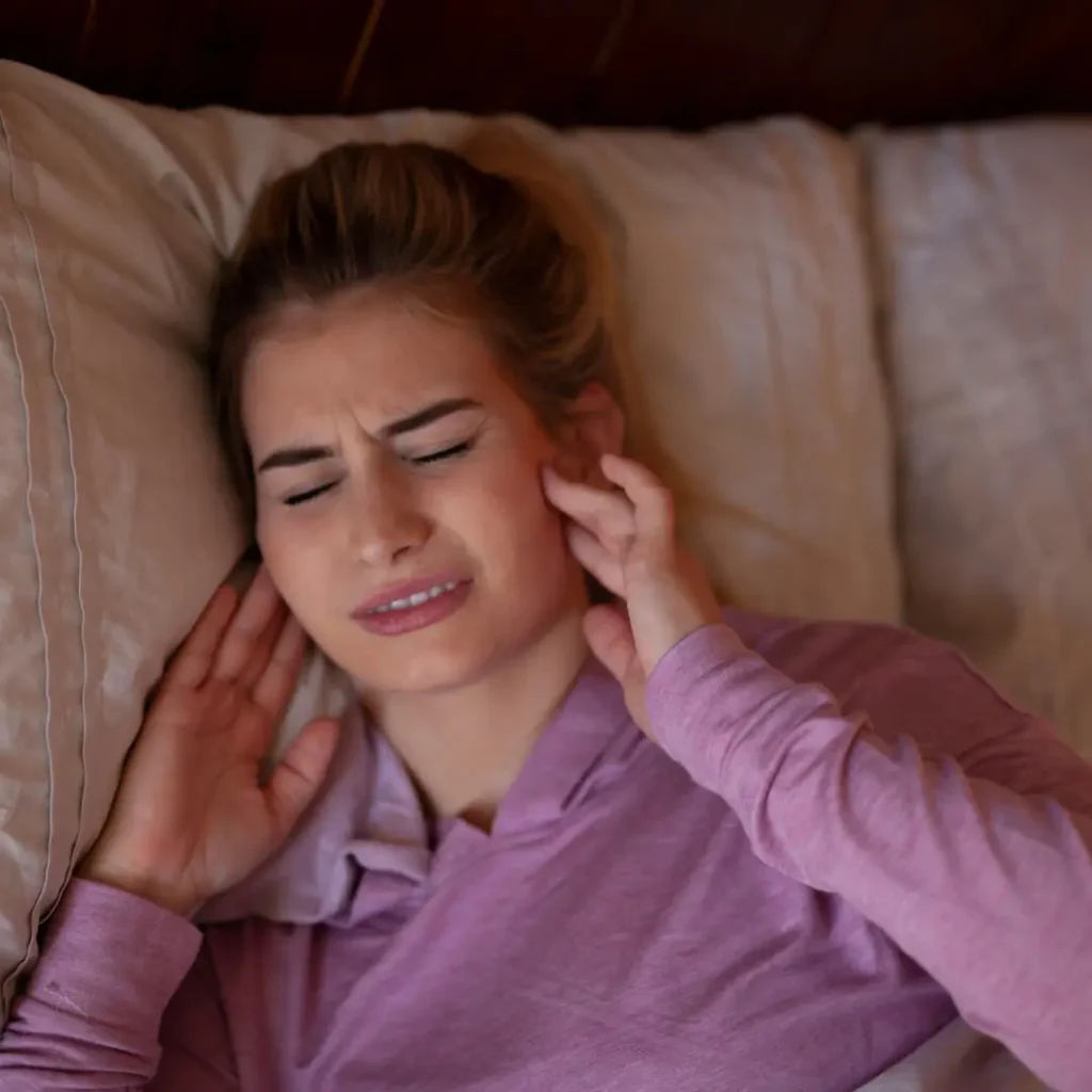 Donna con dolore alle mascelle, evidenzia l'impatto del bruxismo notturno e soluzioni possibili