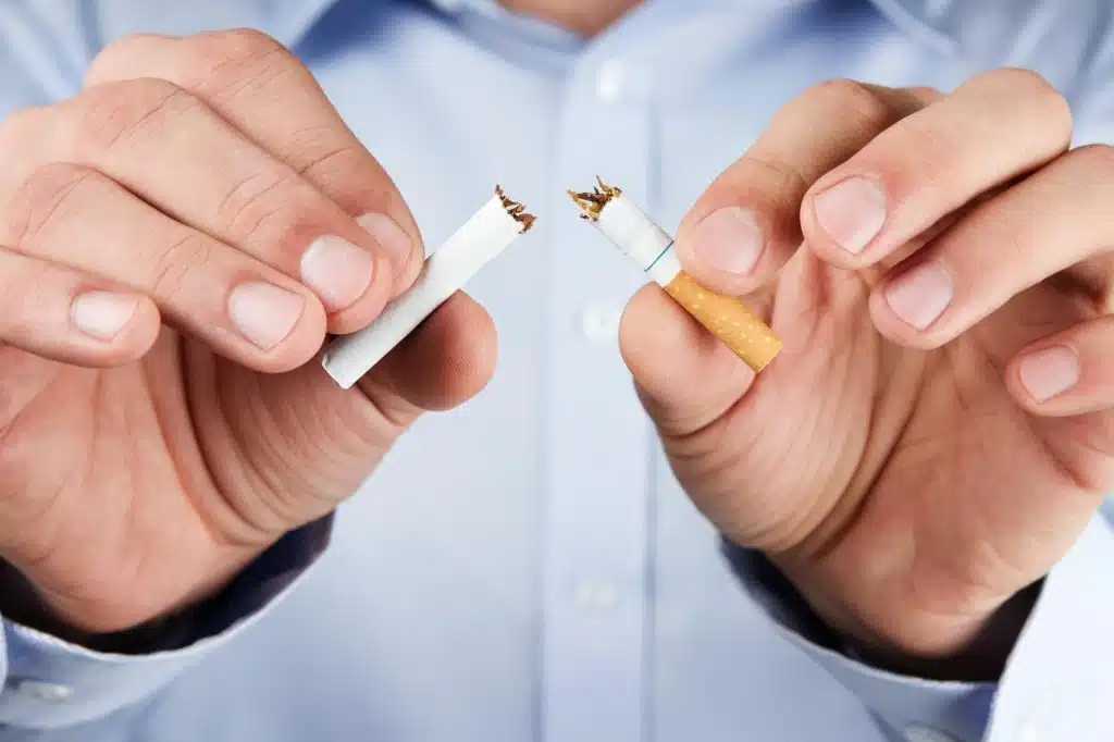 Uomo che spezza una sigaretta per promuovere la salute orale e smettere di fumare.