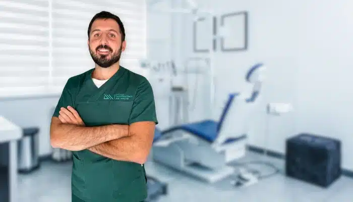 Dottor Del Malvò, esperto di impianti dentali a Torino, in posa nello studio odontoiatrico con attrezzature professionali sullo sfondo.